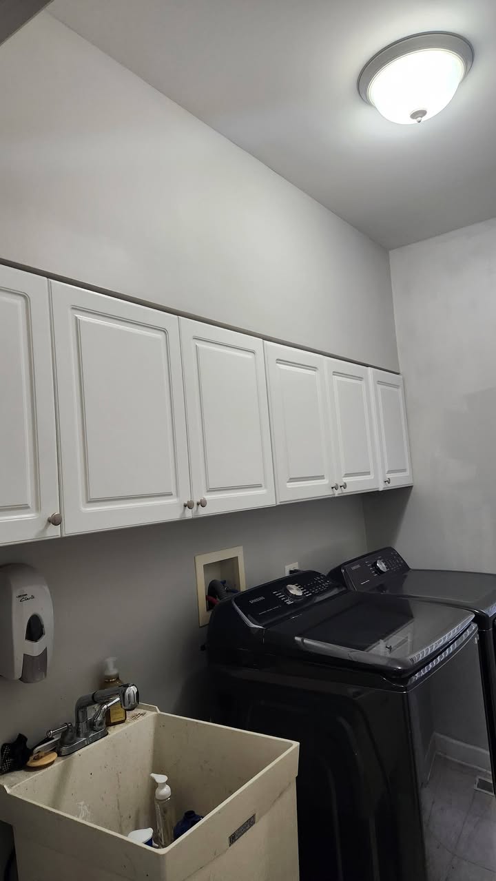 A laundry room after a full repaint, with refinished white cabinets and freshly painted walls.